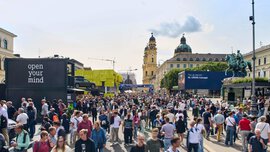 Zahlreiche Messebesucher besuchen Messestände der IAA Mobility auf dem Odeonsplatz in München. Im Hintergrund ist die Theatinerkirche zu sehen.