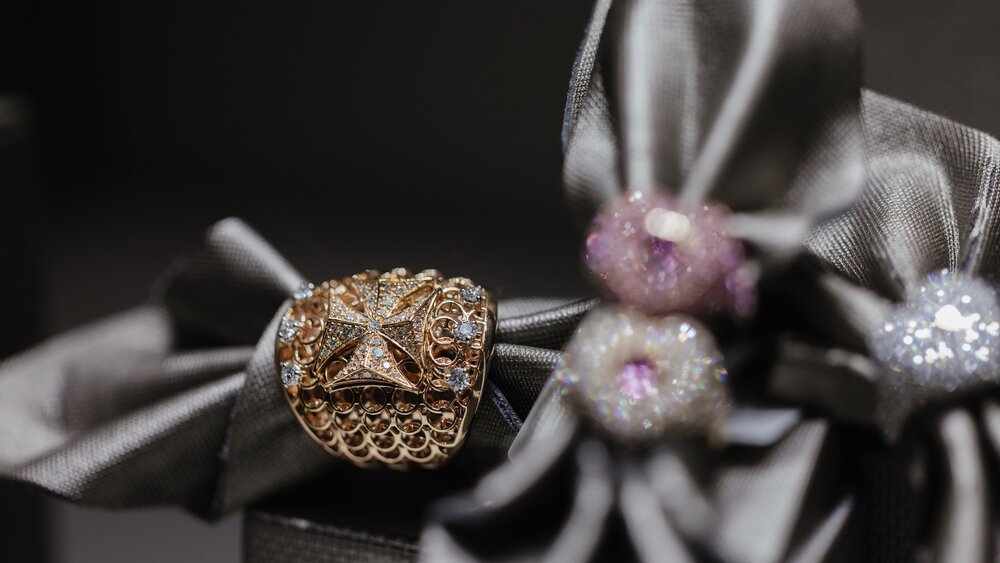 Close-up shots of several shiny pieces of jewelry pinned to a gray cloth and displayed in a showcase.