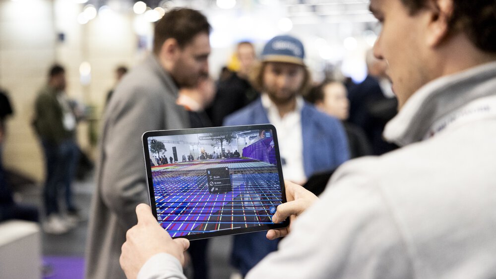 Ein Mann hält ein Tablet, auf dem eine Bauplanungssoftware zu sehen ist.