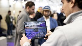 Ein Mann hält ein Tablet, auf dem eine Bauplanungssoftware zu sehen ist.