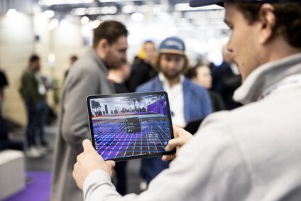 Ein Mann hält ein Tablet, auf dem eine Bauplanungssoftware zu sehen ist.