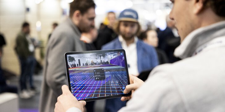 Ein Mann hält ein Tablet, auf dem eine Bauplanungssoftware zu sehen ist.