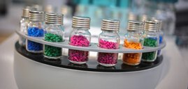 Close-up of an analyzer: Several vials with aluminum septum caps (vials) filled with colored grains are arranged in a circle in round holders.
