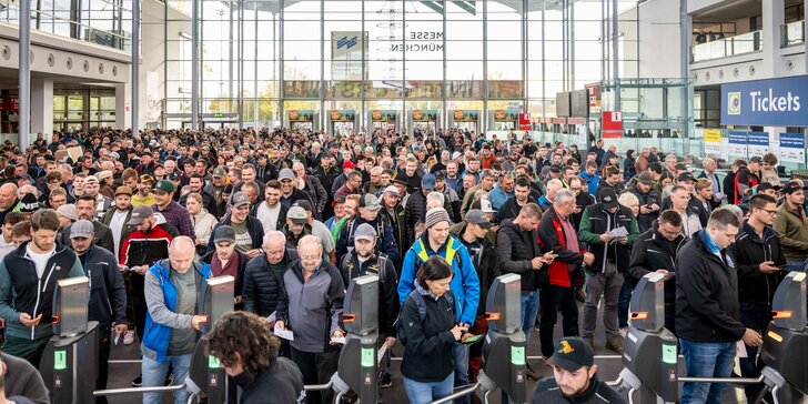 Eine große Menschenmenge, die durch die Drehkreuze am Eingang des Messezentrums Messe München strömt