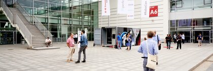 Messebesucher stehen und gehen im Innenhof vor der Halle A6.