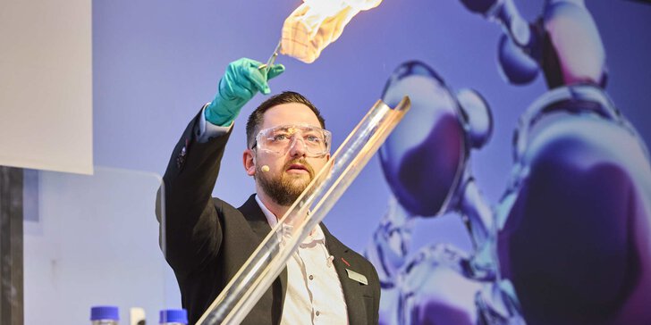 A man in a blazer holds up a metal rod with something burning at the end