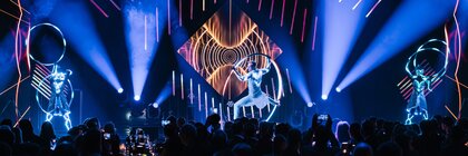 Three artists perform a show with lights and hoops on stage at the INHORGENTA AWARD in front of an audience.