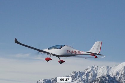 ultralight electric aircraft flying over snow-covered alpine landscape under clear skies
