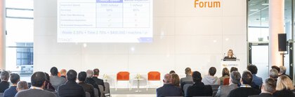 Publikum sieht sich auf einem Forum eine Präsentation mit einer Vergleichstabelle an.
