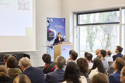 A long-haired person is giving a lecture. Several people listen with interest.