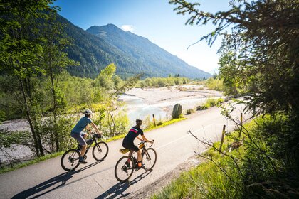 Radfahrende sind auf einer Tagestour entlang der Wasser-Radlwege in Oberbayern unterwegs und genießen die Landschaft an Seen und Flüssen.
