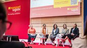 Fünf Frauen in formeller Kleidung sitzen auf einer Bühne der transport logistic vor Publikum und halten eine Diskussion ab.