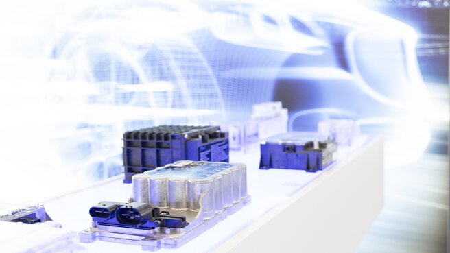 Energy cells displayed on a bright white pedestal, behind them is a wall graphic with a bright white grid of a car.