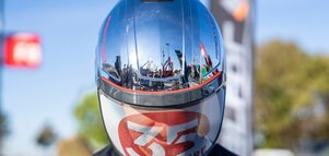 Nahaufnahme eines schwarzen Helms mit spiegelnder Oberfläche, Mesh-Einsatz und roten Akzenten.