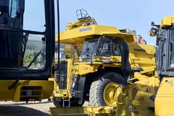 Ein gelber Starrrahmen-Muldenkipper von „Komatsu“ steht zwischen weiteren gelben Fahrzeugen auf dem Freigelände der Messe München während der bauma 2025.