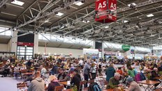 Large beer garden and catering area at the f.re.e trade fair in Hall A5 with numerous visitors at wooden tables, surrounded by stands and decorations.