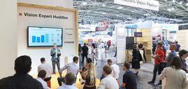Ein Sprecher präsentiert auf der automatica vor Publikum eine Grafik zur KI-basierten Qualitätskontrolle auf einem großen Bildschirm.