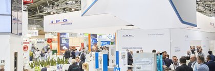 People between well-attended exhibition stands in a brightly lit exhibition hall with the red A3 sign.