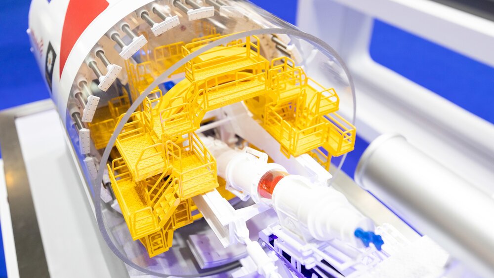 A detailed model of a tunnelling machine with transparent housing shows the internal components.