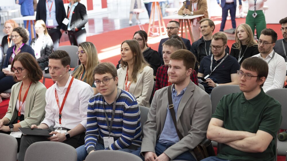 Several spectators sit on chairs during ceramitec and watch a presentation that takes place outside the picture.