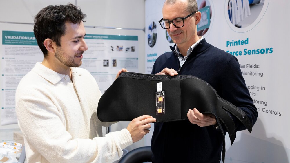 Two exhibitors demonstrating printed force sensor in flexible application at booth