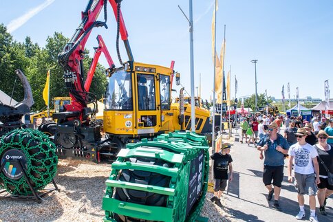 Visitors examine forestry machinery and accessories at a trade show