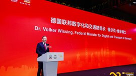 A man in a suit stands at a podium at 