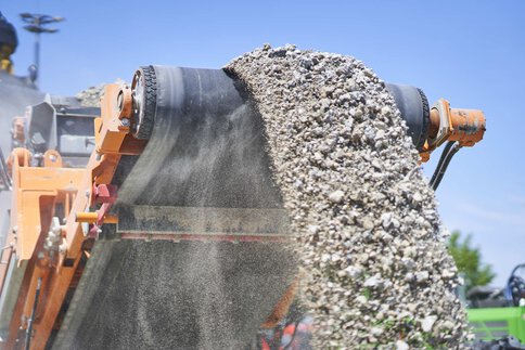 Conveyor belt discharging crushed stone or gravel from an outdoor construction machine.