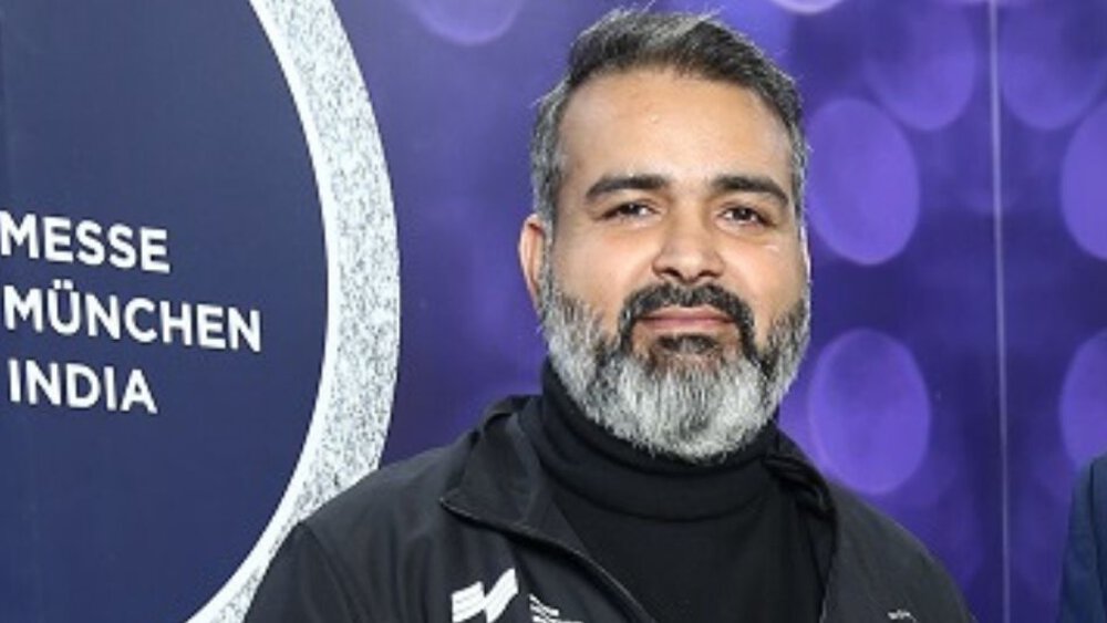 Bhupinder Singh in front of the logo of Messe München India.
