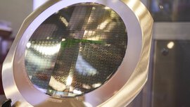 A round construction with a metal frame and many small rectangular, shimmering semiconductor boards.