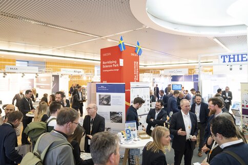 Eine belebte LOPEC Messehalle mit Menschen, die Kontakte knüpfen und an Ausstellungsständen stehen.
