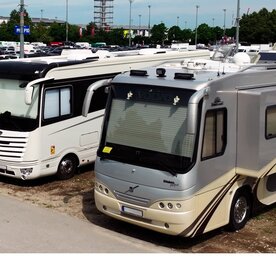 A view across a car park east of the Messe München halls, with numerous parked motorhomes with their blinds down.