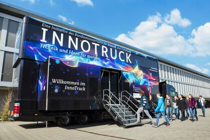A group of young people enter the colourful ‘InnoTruck’ under a blue sky.