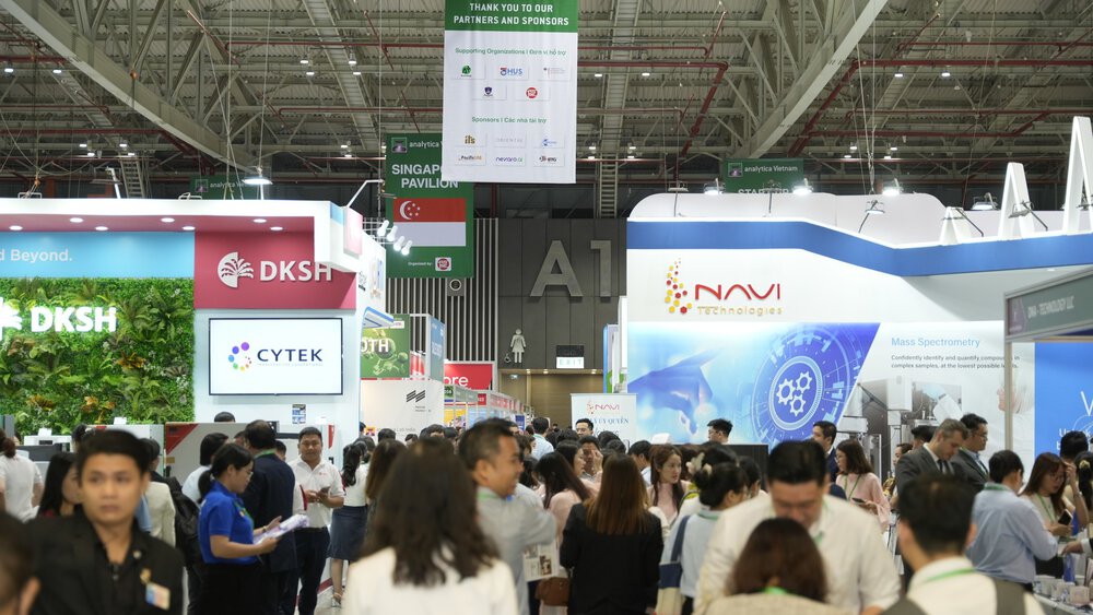 Crowd walks through a busy exhibition hall with stands and exhibitions from various technology companies.