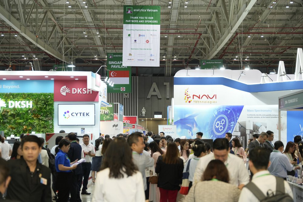 Crowd walks through a busy exhibition hall with stands and exhibitions from various technology companies.