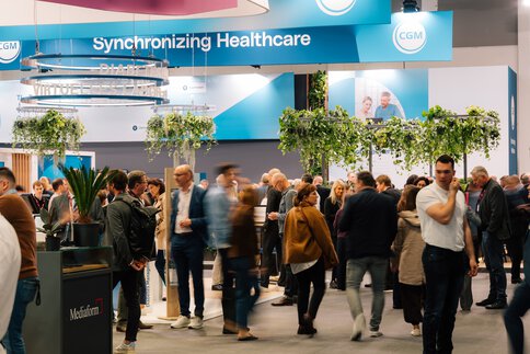Besucher auf der DMEA Messe vor einem Messestand