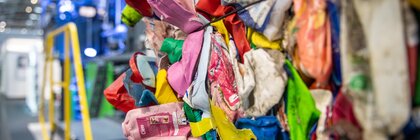 Close-up of a colorful pile of compressed plastic waste in front of a baling press.