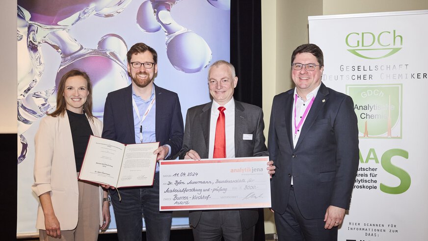 Four people holding a check and laughing into the camera