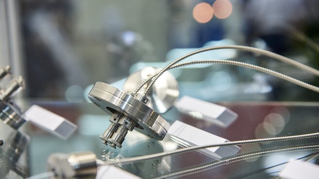 Close-up of a metallic industrial component with connected cables displayed on a reflective surface.