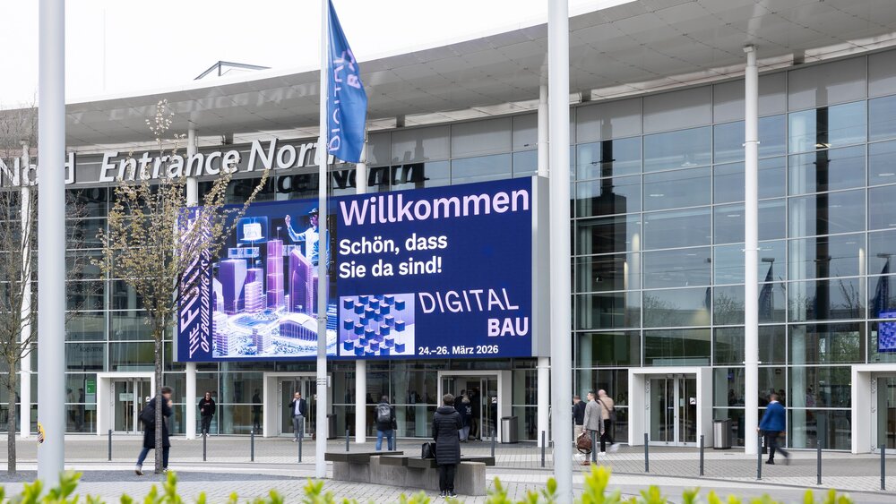 Eingang Kölnmesse mit einem großen Display an der Außenfassade, auf der die digitalBAU ihre Besucher willkommen heißt.