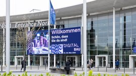 Eingang Kölnmesse mit einem großen Display an der Außenfassade, auf der die digitalBAU ihre Besucher willkommen heißt.