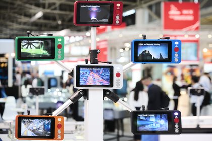 Optical communication technology: Several colored monitors are mounted on a rack and display various applications from science and technology.