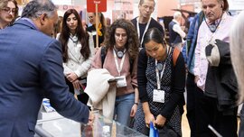Visitor group on a guided tour at LOPEC with “Tour” sign at an exhibition booth