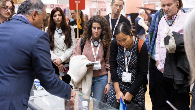 Besuchergruppe bei einer Guided Tour auf der LOPEC mit Rundgang-Schild am Messestand