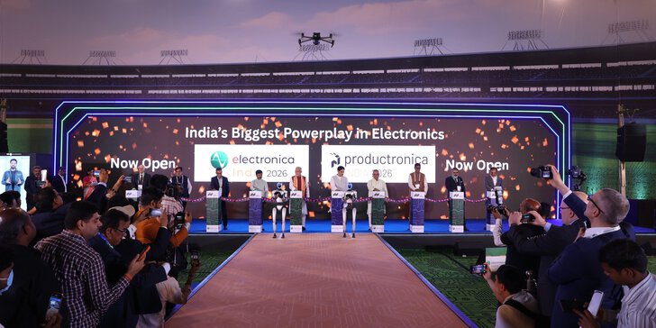 A group of people on stage at the opening ceremony of an electronics trade show, with media and audience members taking photos.