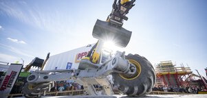 All-terrain construction machine with shovel during a live demonstration on the open-air site.