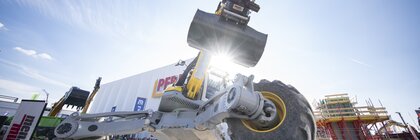 All-terrain construction machine with shovel during a live demonstration on the open-air site.