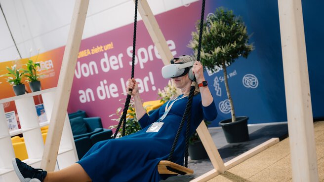 Visitor using a VR headset on a swing in an interactive DMEA area