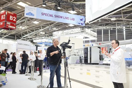 a man in jeans films a person in a lab coat explaining something