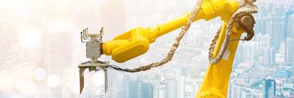 A yellow robot arm in front of a cityscape with tall buildings in the background.